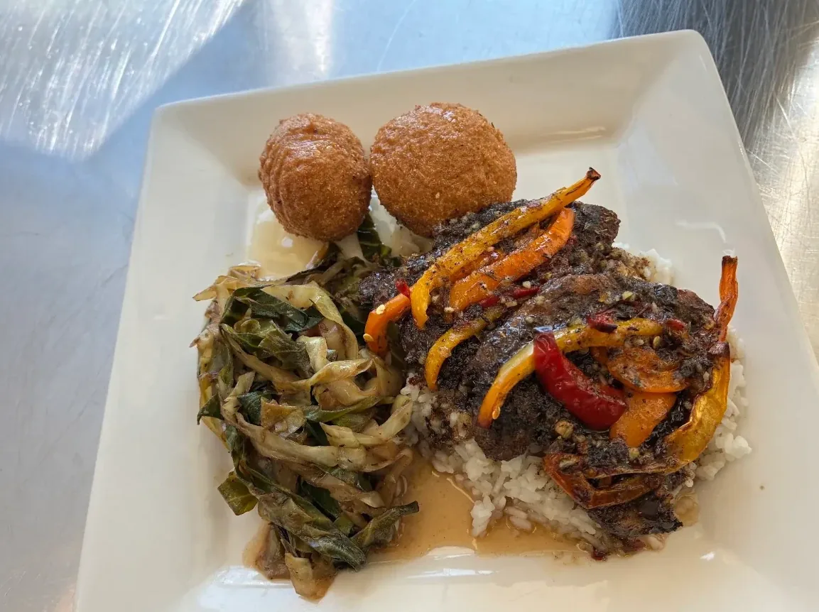 Jerk chicken over white rice with fried cabbage and festival balls